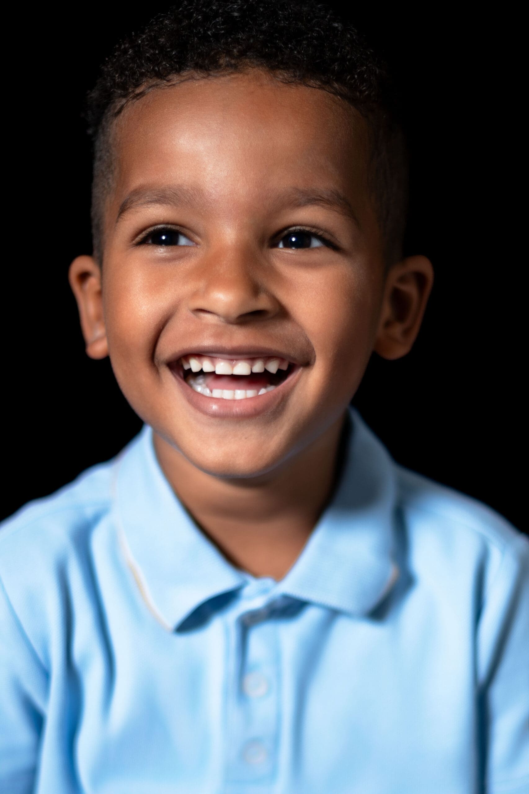 Boy in preschool smiling for fine art school picture.
