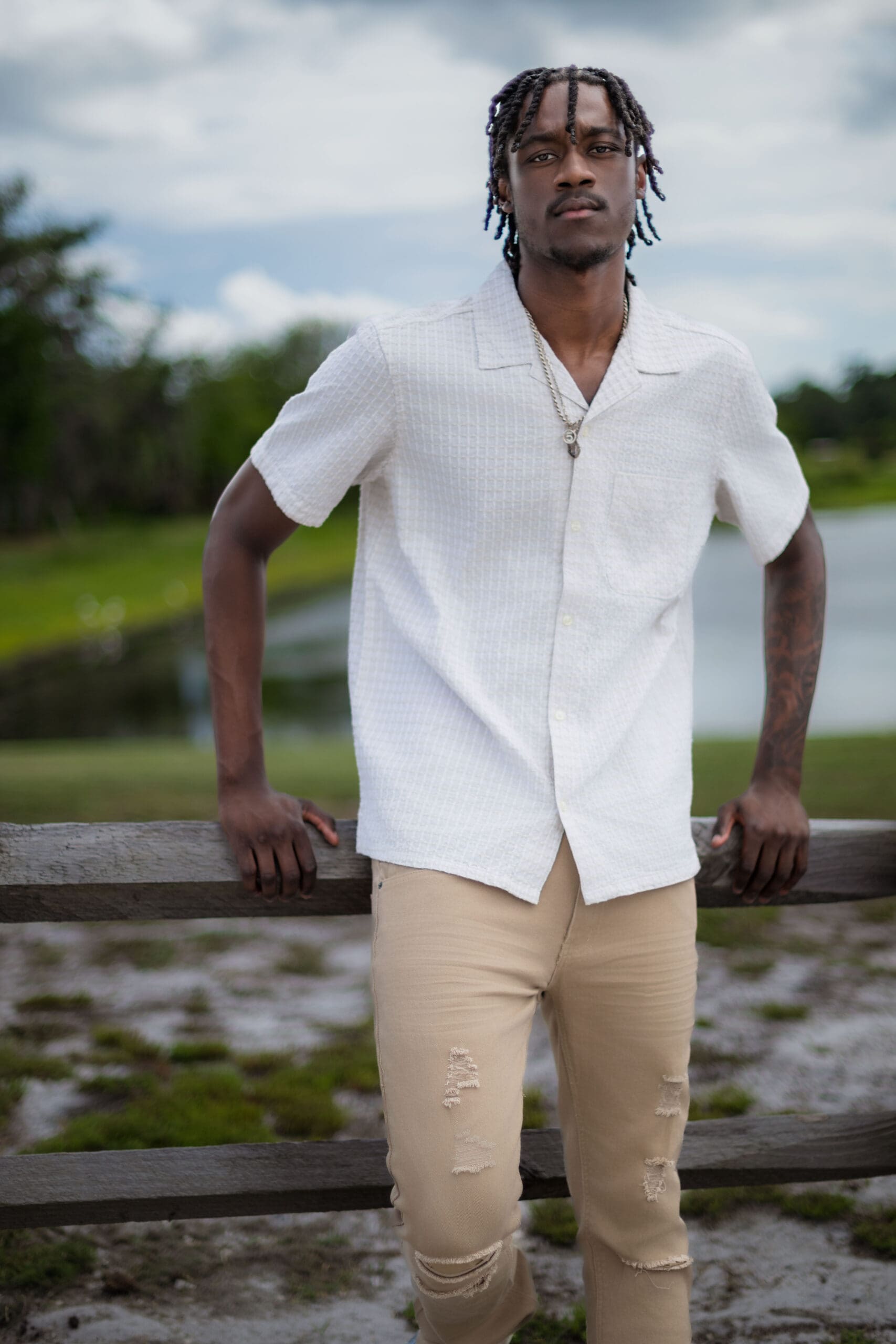 High school senior portrait of a young man standing by a lake during an outdoor senior picture session in Atlanta.
